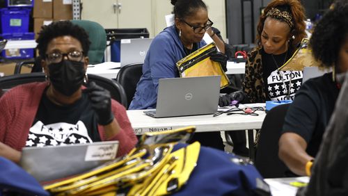 Poll workers prepare to open pouches containing voter memory cards from various precincts at The Fulton County Elections Warehouse on Tuesday, November 8, 2022. (Natrice Miller/natrice.miller@ajc.com)  