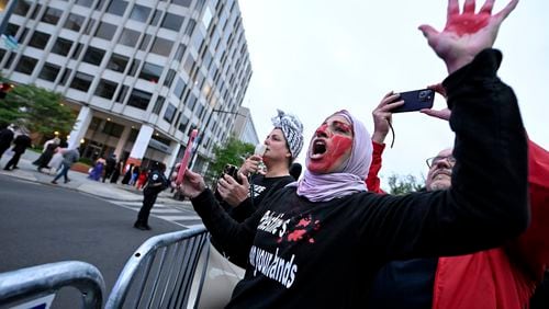 A demonstrator with red paint on their hand and face is seen behind a police barricade during a pro-Palestinian protest over the Israel-Hamas war at the White House Correspondents' Association Dinner, Saturday April 27, 2024, in Washington. (AP Photo/Terrance Williams)