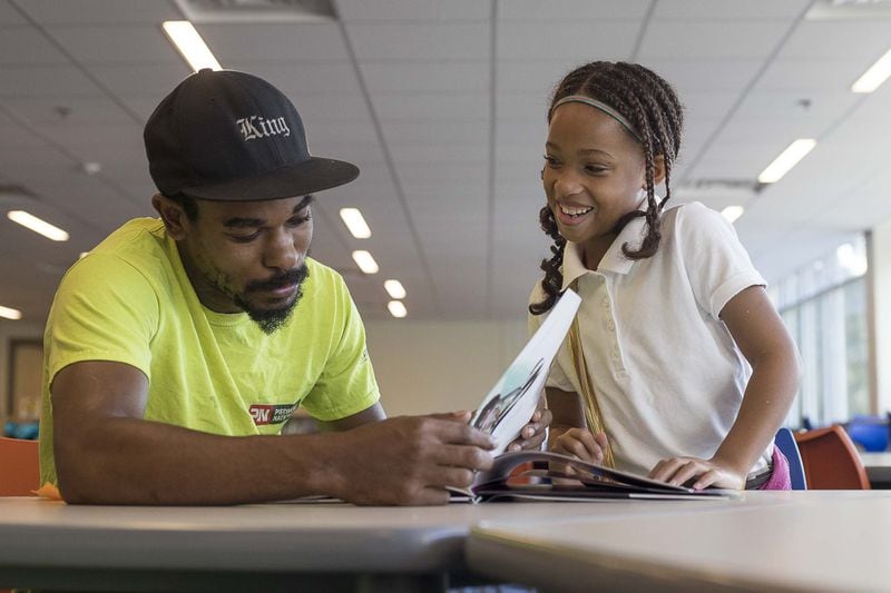 Gary Jackson reads the book “Hair Love” to his fourth grade daughter Melasia Jackson during an event at Harper-Archer Elementary School on Monday, Sept. 9, 2019. (ALYSSA POINTER/ALYSSA.POINTER@AJC.COM)