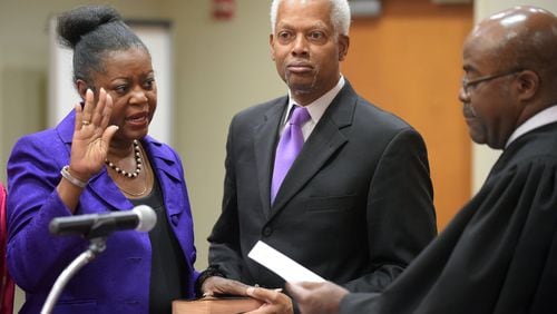 Incoming DeKalb Commissioner Mereda Davis Johnson stands with her husband, U.S. Rep. Hank Johnson, as she is sworn in by DeKalb Superior Court Judge Gregory A. Adams on Monday. Her election brings the county commission to a full seven members for the first time in more than two years. KENT D. JOHNSON /KDJOHNSON@AJC.COM