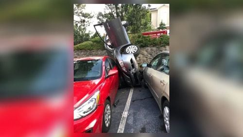 A car went over a ledge and crashed between two parked vehicles Monday at an apartment complex in Cobb County. Credit: Cobb County Fire and Emergency Services