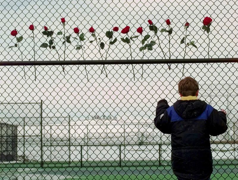 FILE - A boy looks through the fence at the Columbine High School tennis courts in Littleton, Colo., April 24, 1999. Twenty-five years later, The Associated Press is republishing this story about the attack, the product of reporting from more than a dozen AP journalists who conducted interviews in the hours after it happened. The article first appeared on April 22, 1999. (AP Photo/Eric Gay, File)