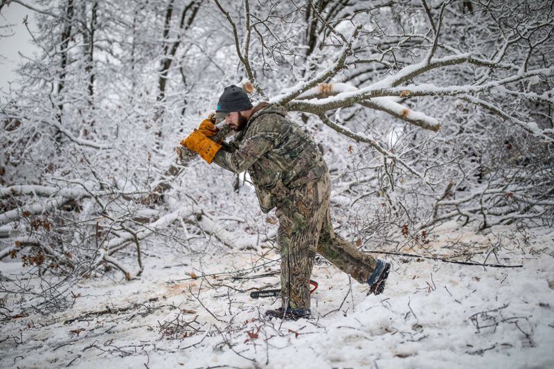 Cory Dodson works to clear a fallen tree Saturday on Wooten Lake Road in Kennesaw. Power outages hit Cobb County as well as other parts of metro Atlanta and North Georgia after snow and ice swept into the area starting Friday, Dec. 8, 2017.