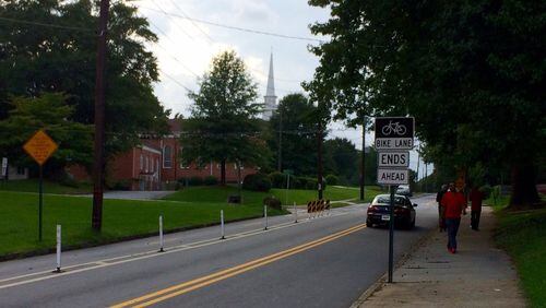 A sign warns bicyclists that a protected bike lane is about to end. A church in Atlanta requested removal of some of the lanes, saying they obstructed the congregation driving in and out. Others saw it as a sign of gentrification. (Photo by Bill Torpy)