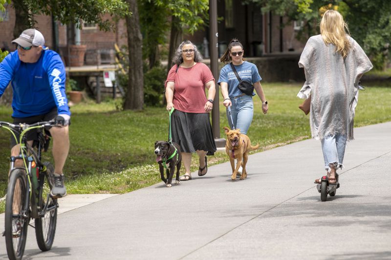 In this file photo, Kim Brown, left, and her daughter Katie Brown walk their dogs without a mask while walking along the Atlanta BeltLine in Atlanta’s Old Fourth Ward community. Both of them say they are fully vaccinated and feel comfortable not wearing a face covering when outside.  (Alyssa Pointer / Alyssa.Pointer@ajc.com)
