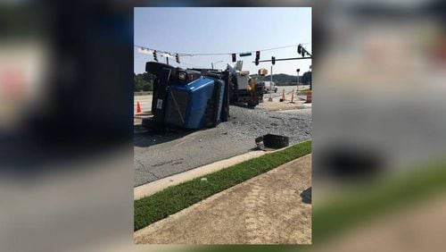 A dump truck ran a red light, overturned and spilled 18 tons of gravel on the I-20 overpass at West Avenue, according to Conyers police.