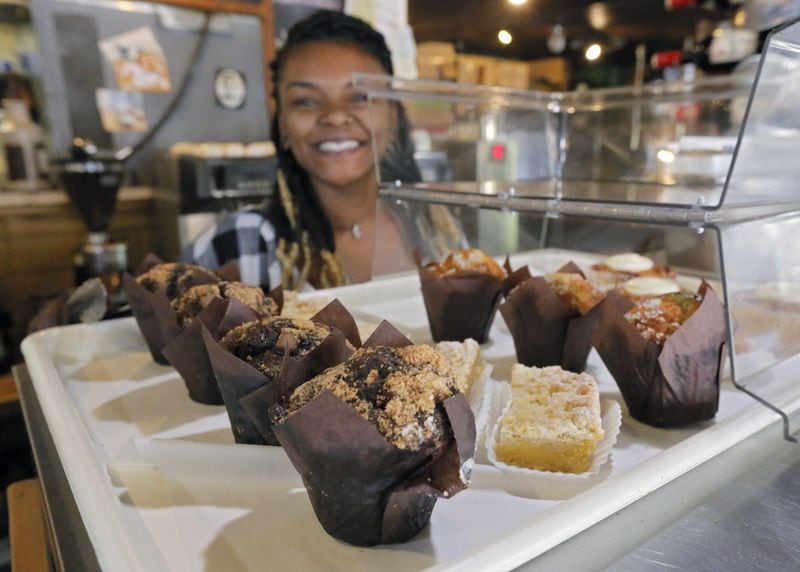 Chanel Hayes, barista at ParkGrounds, offers some pastries and muffins. ParkGrounds, on Flat Shoals Avenue in Atlanta, is a coffee shop, restaurant and dog park rolled into one. BOB ANDRES /BANDRES@AJC.COM