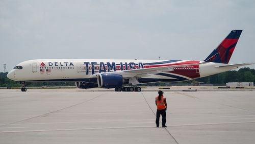 A Delta ramp agent looks at an Airbus A350 decorated in a new Team USA livery celebrating the Paris Olympics as it lands at Hartsfield-Jackson Atlanta International Airport on Friday, May 3, 2024. (Elijah Nouvelage for The Atlanta Journal-Constitution)