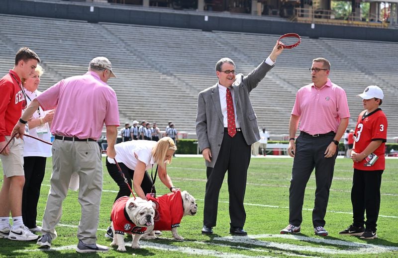Jere Morehead, President of the University of Georgia, holds up a collar as Boom (right), a 10-month-old English Bulldog, as Uga XI, is introduced during pregame ceremonies at the G-Day game at Sanford Stadium, Saturday, April 15, 2023, in Athens. Boom will succeed Uga X (left), known as Que, who will retire as the winningest mascot in Georgia history. (Hyosub Shin / Hyosub.Shin@ajc.com) 