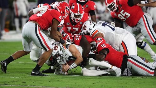 Georgia defenders pile on Auburn quarterback Bo Nix for no gain during the first quarter of Saturday's game in Athens. Georgia kept Auburn out of the end zone and only allowed a pair of field goals in the 27-6 victory. (Curtis Compton/AJC)