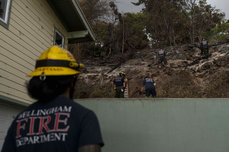 FILE - Firefighters clear debris in Kula, Hawaii, Tuesday, Aug. 15, 2023, following wildfires that devastated parts of the Hawaiian island of Maui. The Maui Fire Department is expected to release a report Tuesday, April 16, 2024, detailing how the agency responded to a series of wildfires that burned on the island during a windstorm last August. (AP Photo/Jae C. Hong, File)