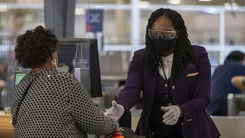 A Delta Air Lines employee handles a passenger's luggage while wearing goggle, gloves and a face mask in the domestic terminal at Hartsfield-Jackson Atlanta International Airport in Atlanta on Monday, Nov. 23, 2020. (Alyssa Pointer/Atlanta Journal-Constitution/TNS)