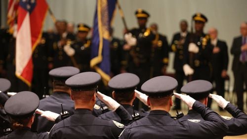 March 18, 2015 Atlanta: Atlanta Police recruits salute during the presentation of colors before their graduation ceremony Wednesday evening March 18, 2015 at North Atlanta High School. Ben Gray / bgray@ajc.com