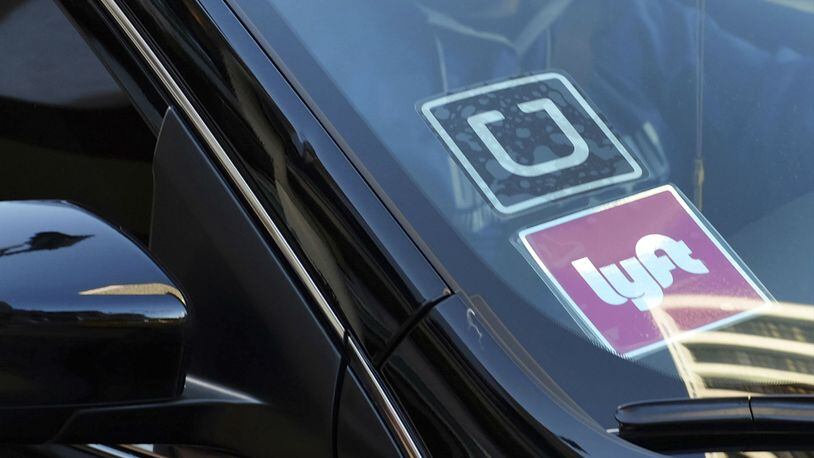 A ride-share car displays Uber and Lyft stickers on its front windshield in a 2016 photo taken in downtown Los Angeles. A federal civil jury on Tuesday, May 21, 2019, found a former Somali army colonel, Yusuf Abdi Ali, liable for the torture of a Somali farmer when he was 17 years old in 1987. Ali, who now lives in Fairfax, Virginia, was working for Uber as his trial began and had previously worked for Lyft and as a security guard at Dulles International Airport near Washington, D.C. Ali was ordered to pay his victim, Farhan Warfaa $500,000 in damages.