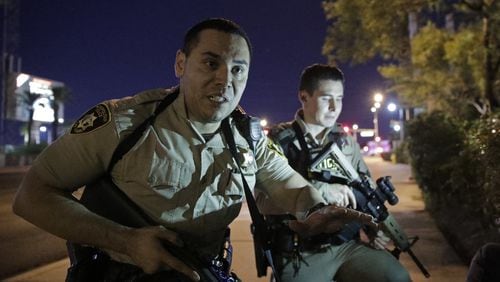 Police officers advise people to take cover near the scene of a shooting near the Mandalay Bay resort and casino on the Las Vegas Strip, Sunday night in Las Vegas. (AP Photo/John Locher)
