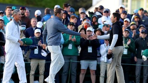 Scottie Scheffler, center, and Charl Schwartzel greet after their third round on the eighteenth green of the Masters at Augusta National Golf Club on Saturday, April 9, 2022, in Augusta. (Curtis Compton / Curtis.Compton@ajc.com)
