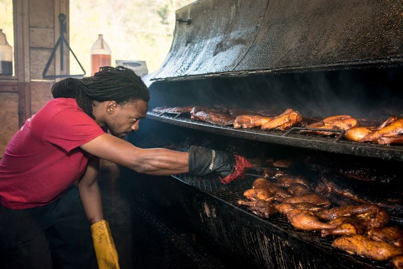 Chef Bryan Furman, shown arranging meat on the smoker at B’s Cracklin Barbecue in Atlanta, plans to rebuild after Wednesday’s fire at his restaurant. CONTRIBUTED BY MIA YAKEL