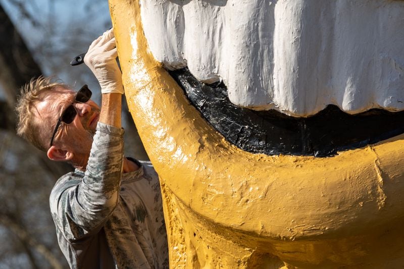Plains resident Michael Dominick paints the Smiling Peanut in Plains on Sunday. The 13-foot statue is made out of hard Styrofoam and has moved around the city over the past 40 some years. (Arvin Temkar / arvin.temkar@ajc.com)