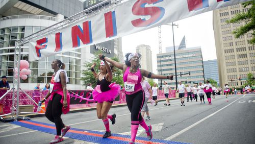 Chi Michaels (right) and Leesa Mendes hold hands as they cross the finish line for the Susan G. Komen Race for the Cure at Lenox Square Mall on Saturday, May 10, 2014.