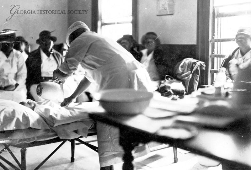 Midwife Georgia Barron conducts a demonstration during a midwife class in 1938. Barron, who practiced as a midwife from 1898-1938, uses a pitcher with a manikin in preparation for childbirth. The photo's original caption states that "The necessity for cleanliness is emphasized." (Courtesy of the Georgia Historical Society, MS 55-VM01-02-556)