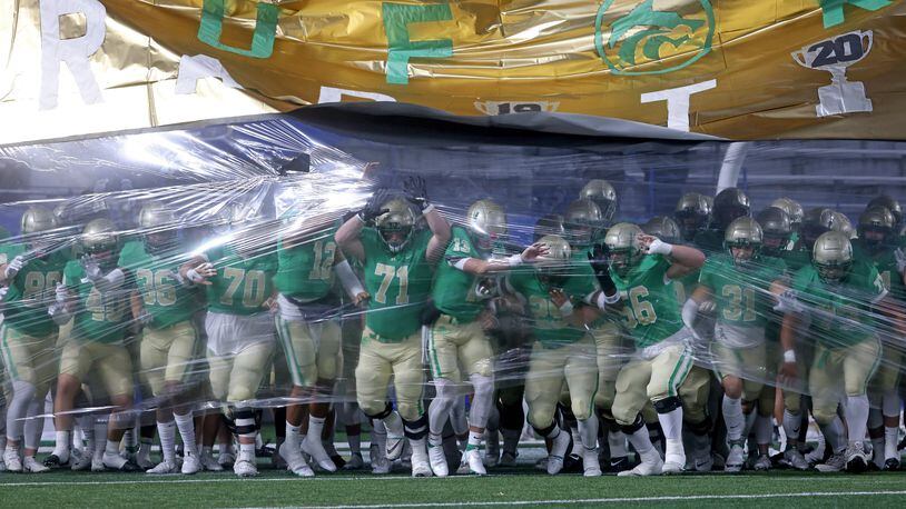 Buford players burst through the banner before their title game against Langston Hughes in the Class 6A state playoffs in December. Buford, which won the last two state titles in the class, is leaving for Class 7A. (JASON GETZ / FOR THE ATLANTA JOURNAL-CONSTITUTION)