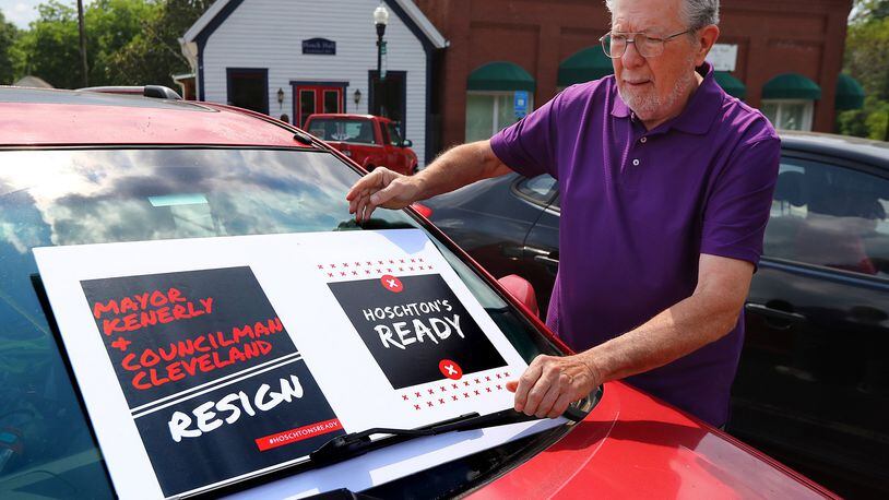 Hoschton resident Russ Zyga puts a sign on his car in front of City Hall Wednesday. The Jackson County Democratic and Republican parties were holding a joint event nearby to show residents how to file ethics complaints against two city officials whose racially charged remarks drew criticism nationwide. CURTIS COMPTON/ccompton@ajc.com