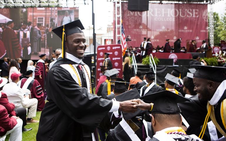 A Morehouse College graduate shakes the hand of a friend during the Morehouse College commencement ceremony on Sunday, May 21, 2023, on Century Campus in Atlanta. The graduation marked Morehouse College's 139th commencement program. CHRISTINA MATACOTTA FOR THE ATLANTA JOURNAL-CONSTITUTION