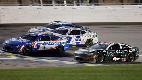 Kyle Larson (5) crosses the finish line milliseconds in front of Chris Buescher (17) for the win during a NASCAR Cup Series auto race at Kansas Speedway in Kansas City, Kan., Sunday, May 5, 2024. (AP Photo/Colin E. Braley)
