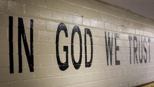 This July 23, 2019 photo shows "In God We Trust" stenciled in a wall at South Park Elementary in Rapid City, S.D. Louisiana has a similar law as South Dakota that requires the display of the national motto.
