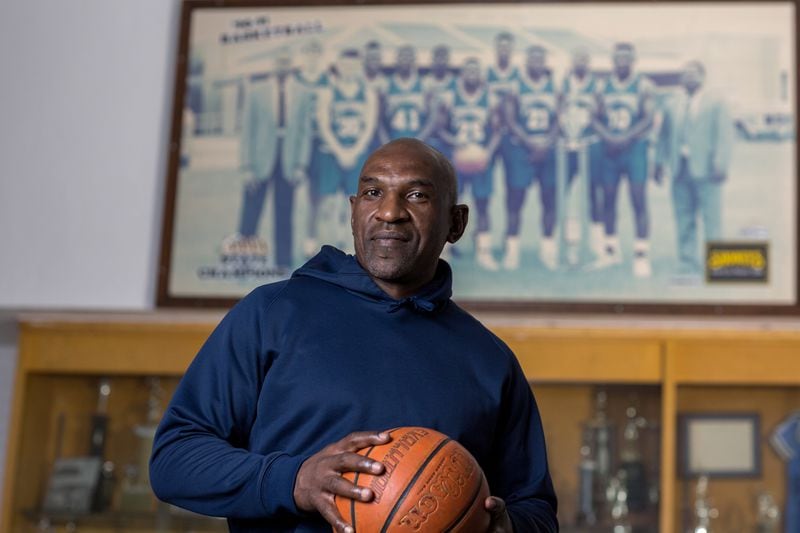 Keith Legree, the star player on the Statesboro high school’s 1991 State Championship team, returned to take the place of his mentor coach Lee Hill, who died of COVID-19 in August 2020. In back, a portrait of the championship team depicts Coach Hill at the far right. (AJC Photo/Stephen B. Morton)