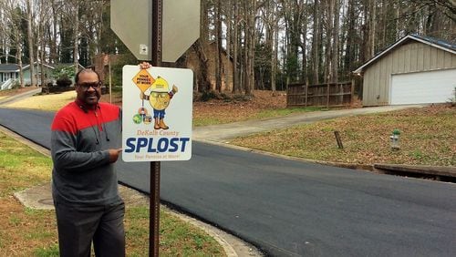 Harold Hardee stands next to a SPLOST sign posted at Golfbrook and Fieldgreen Drives in Stone Mountain. Golfbrook is among the first 10 miles of roads to be resurfaced under the SPLOST program. CONTRIBUTED
