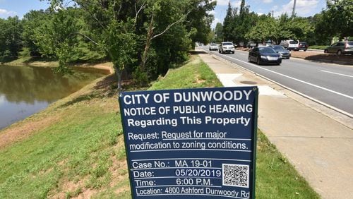 A “Notice of Public Hearing” sign is posted near Ashford Dunwoody Road in Dunwoody  where developers hope to redevelop an old restaurant hub in the Perimeter Center area, adding a gas station, grocery store, a bank and a new road. HYOSUB SHIN / HSHIN@AJC.COM
