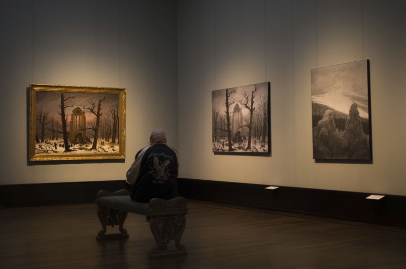 A man sits in front of a copy of Caspa David Friedrich's painting Monastery Cemetery In Snow' during a press preview of the exhibition 'Caspar David Friedrich. Infinite Landscapes' at the Alte Nationalgalerie museum in Berlin, Germany, Germany, Wednesday, April 17, 2024. A major show of Caspar David Friedrich's iconic landscapes that marks the 250th anniversary of his birth is opening in Berlin, the city where he made his breakthrough and where an exhibition in 1906 kicked off an an enduring revival in interest in the German Romantic master. (AP Photo/Markus Schreiber)