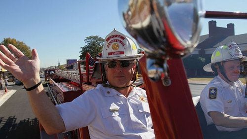 Marietta Fire Chief Jackie Gibbs waves at the crowd in the 1949 fire truck driven by Assistant Fire Chief Scott Tucker along Roswell Street in 2010. Gibbs will retire after 40 years with the department.