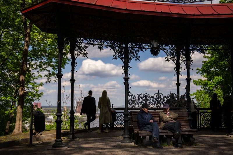 Two men chat on a bench at Saint Volodymyr Hill park in Kyiv, Ukraine, Saturday, April 20, 2024. (AP Photo/Francisco Seco)