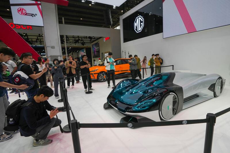 Visitors take photos of a MG concept car during an opening of China Auto Show in Beijing, China, Thursday, April 25, 2024. (AP Photo/Tatan Syuflana)