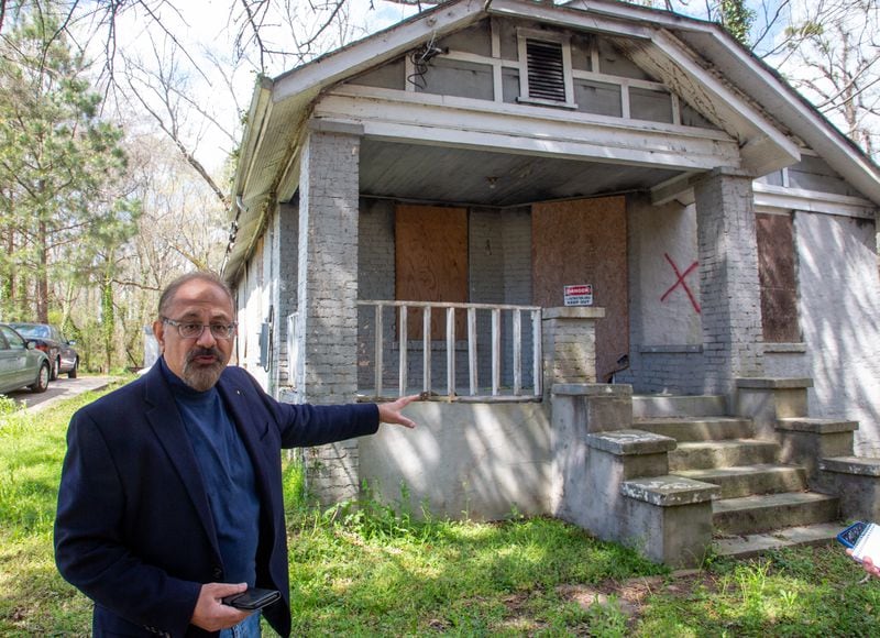 Swapan Kumar stands in front of of home he owns in southwest Atlanta home that the city has marked for demolition Friday, March 25, 2022. Kumar got the notice it was being considered for demolition just weeks after he bought it. STEVE SCHAEFER FOR THE ATLANTA JOURNAL-CONSTITUTION