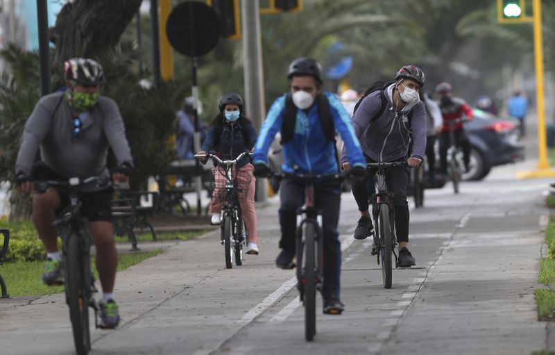 Commuters wearing masks as a precaution amid the spread of COVID-19 ride their bicycles in the Miraflores area of Lima. (AP Photo/Martin Mejia)