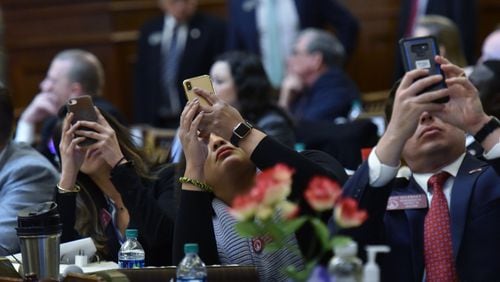 Reps. (from left) Bee Nguyen, Renitta Shannon and Mike Wilensky take  pictures of the result as they vote on HB 481, which would outlaw abortions once a doctor can detect a heartbeat in the womb, in the House Chambers during Crossover day at the Capitol on Thursday, March 7, 2019. HYOSUB SHIN / HSHIN@AJC.COM