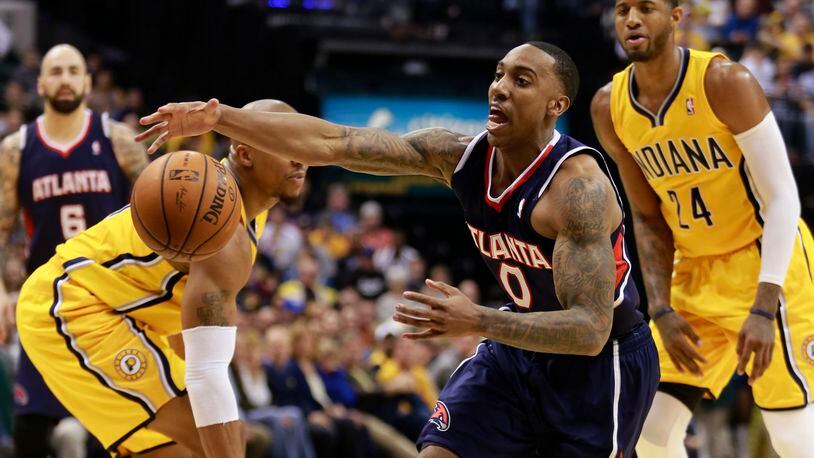 Atlanta Hawks guard Jeff Teague (0) reaches for the basketball after driving between Indiana Pacers forward Paul George, right, and Pacers forward David West in the first half of an NBA basketball game in Indianapolis, Sunday, April 6, 2014. (AP Photo/R Brent Smith)