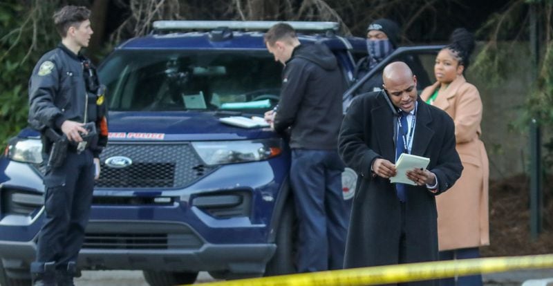 Atlanta police Lt. Ralph Woolfolk (right) takes a phone call on the scene of a deadly shooting in the area of Hunnicutt Street and Centennial Olympic Park Drive on Tuesday morning.