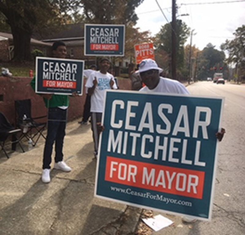 Reginald Mundy is carrying a sign for Ceasar Mitchell for mayor in the Atlanta race.