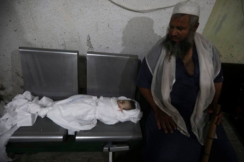 EDS NOTE: GRAPHIC CONTENT - A Palestinian man sits while mourning his relative killed in the Israeli bombardment of the Gaza Strip at the morgue of the Kuwaiti Hospital in Rafah refugee camp, southern Gaza Strip, early Saturday, April 20, 2024. (AP Photo/Ismael Abu Dayyah)