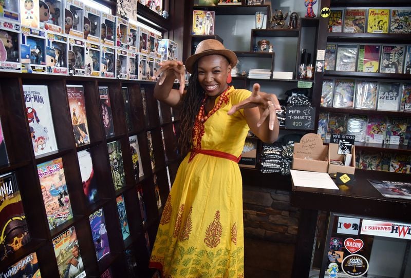 Comic book artist Afua Richardson strikes a superhero pose surrounded by the inventory at My Parents’ Basement, a restaurant/comic book store in Avondale Estates. HYOSUB SHIN / HSHIN@AJC.COM