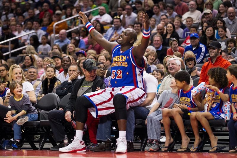 Harlem Globetrotter big man Big Easy Lofton, all 6-foot-9 and 250 pounds of him, playfully takes a courtside seat, ignoring the fan already sitting there. CONTRIBUTED BY HARLEM GLOBETROTTERS