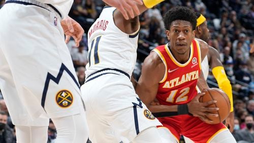 Atlanta Hawks forward De'Andre Hunter, right, looks to pass the ball as Denver Nuggets guard Monte Morris defends during the first half of an NBA basketball game Friday, Nov. 12, 2021, in Denver. (AP Photo/David Zalubowski)