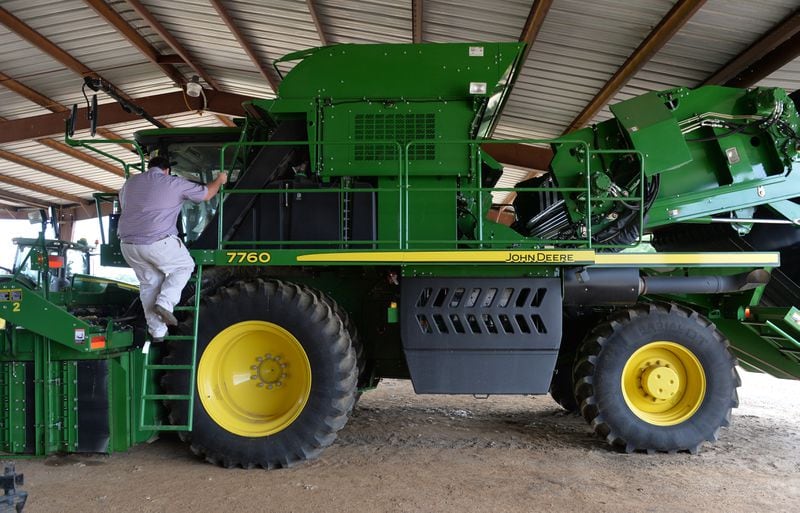 Matt Coley climbs aboard his John Deere cotton picker in 2015. The machine, with a price tag of around $700,000, is the heart of the family farm. BRANT SANDERLIN / AJC