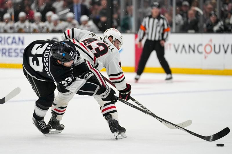 Los Angeles Kings right wing Viktor Arvidsson (33) and Chicago Blackhawks center Colin Blackwell (43) reach for the puck during the second period of an NHL hockey game Thursday, April 18, 2024, in Los Angeles. (AP Photo/Ashley Landis)