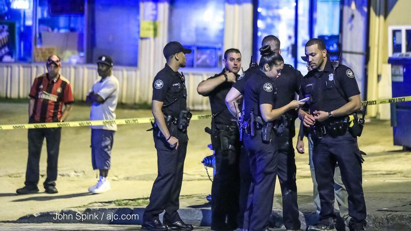 Atlanta police officers investigate a triple shooting at the Quick Pick convenience store near the Greyhound bus station on Forsyth Street.