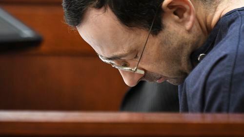 Larry Nassar hangs his head as a former gymnast details how he abused her.  For decades after victims first told state employees of his abuse, a code of silence protected the physician as he went on to sexually violate some 250 girls and women. Some states are now considering measures to prevent such predators.  (Matthew Dae Smith/Lansing State Journal via AP)